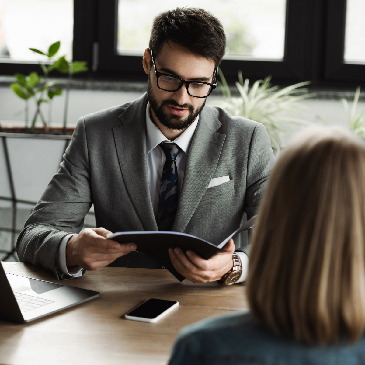 a man looking at a file while talking to a women who is sitting in front of him