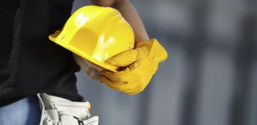 Person holding a plastic yellow helmet
