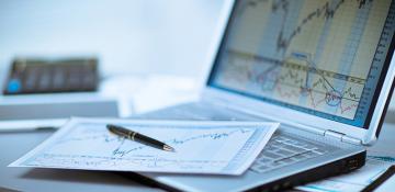 Pen and paper on top of a laptop showing graphs