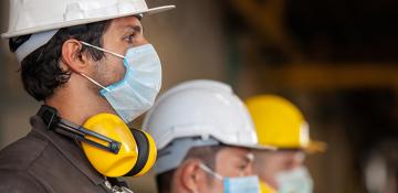 Line of 3 male workers in hard hats and masks