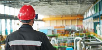 Back of man with red hardhat overseeing large storage room