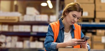 Woman looking at phone in warehouse