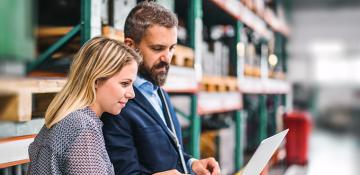 people in a warehouse looking at a laptop